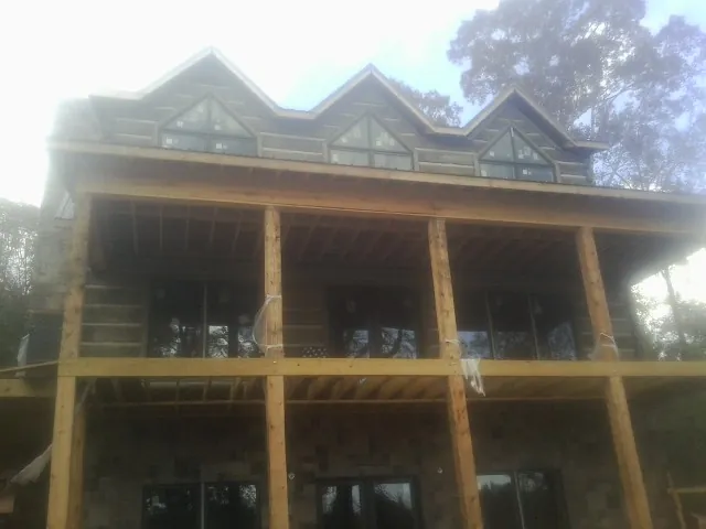 Dormers and porch framing on a large log home under construction — Roof Coating work by our crew in Bethel