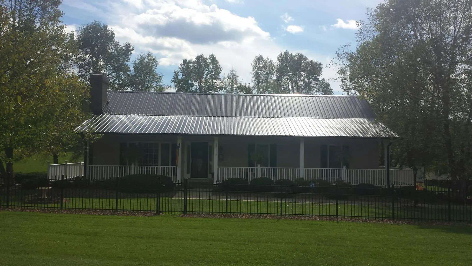 Gray metal roof on a brick ranch with a full width front porch — Gutter Guard Installation work by our crew in Bethel